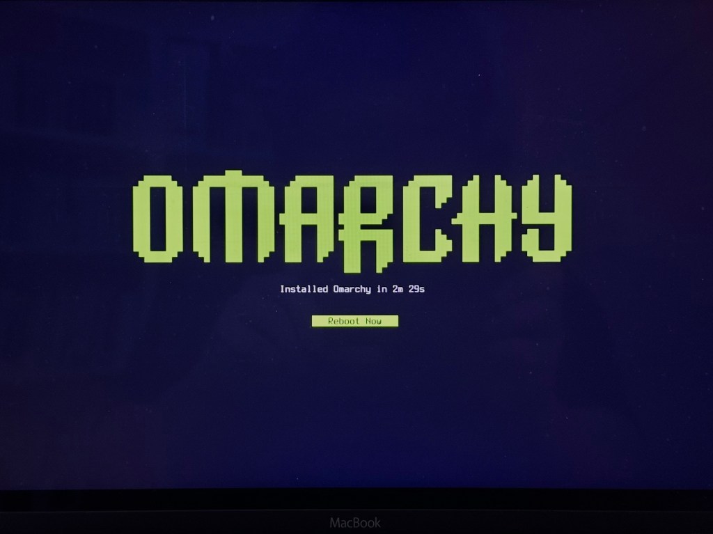 Omarchy installation screen on a 12-inch MacBook, showing the installation completed in 2 minutes and 29 seconds.
